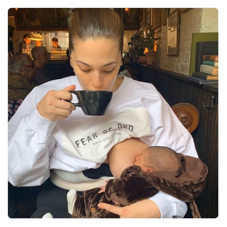 Maman boit son café pendant que bébé tète