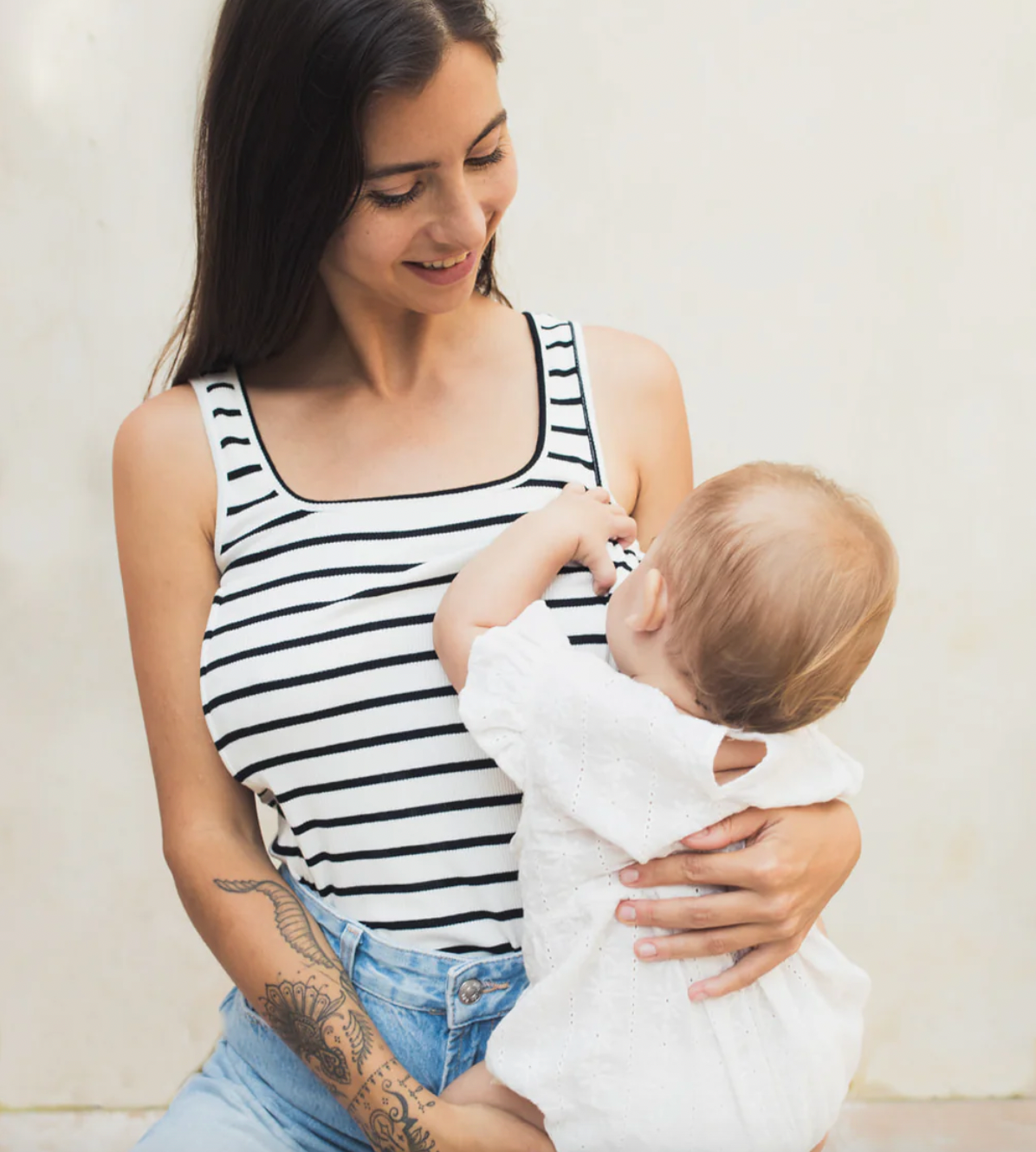 Woman breastfeeding her baby in a striped nursing tank top