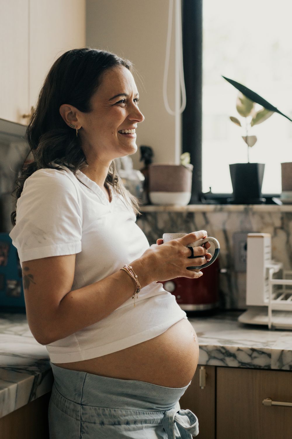 femme enceinte souriant avec une tasse à la main