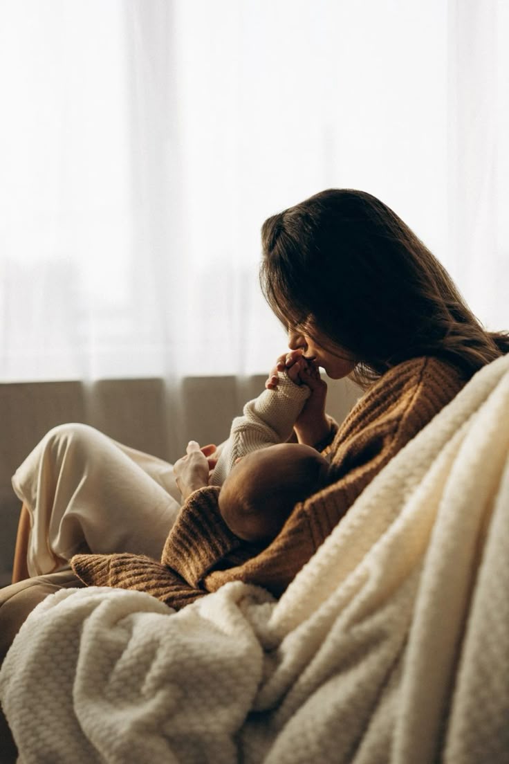 Femme qui allaite son bébé et qui lui fait un bisous sur la main