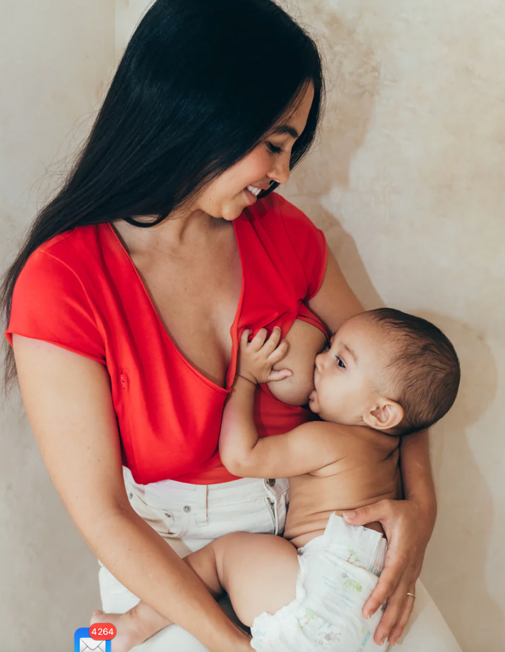 Photo d'une mère donnant le sein à son enfant, vêtue d'un t-shirt d'allaitement.