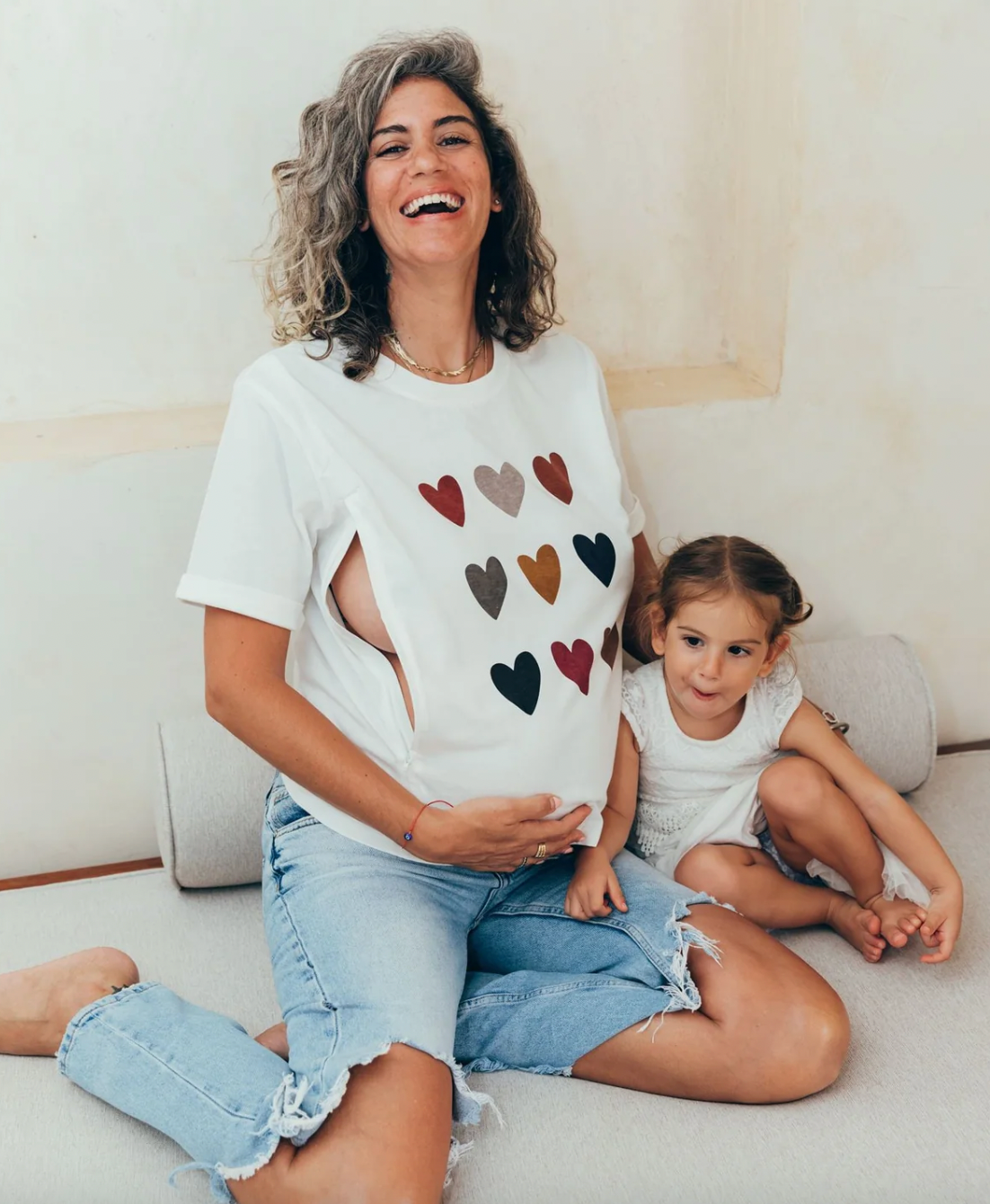 Fotografie einer entspannten Mutter, die mit einer bequemen Jeans und einem Stillshirt bekleidet ist