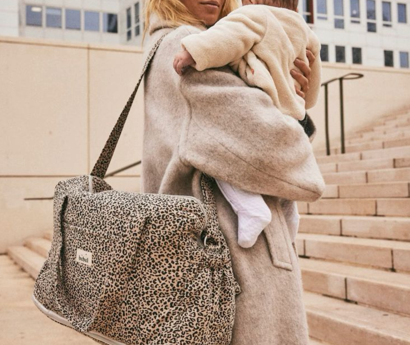 Fotografie einer Mutter, die ihr Kind trägt, mit einer Umhängetasche für die Mutterschaft.