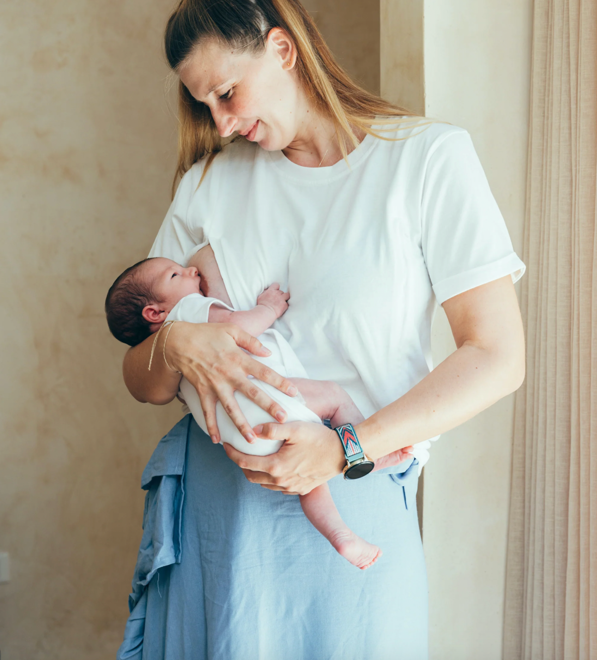 Photographie d'une mère en train d'allaiter son enfant grâce à un t-shirt d'allaitement.