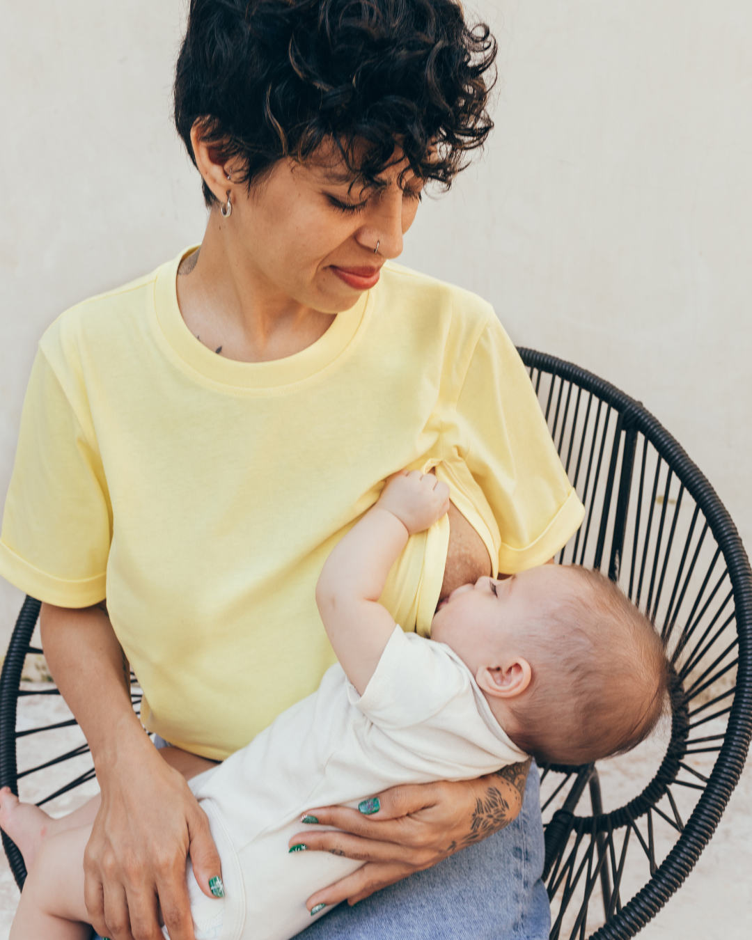 Photo of a young mother in a sunny yellow Breastfeeding t-shirt breastfeeding her baby.