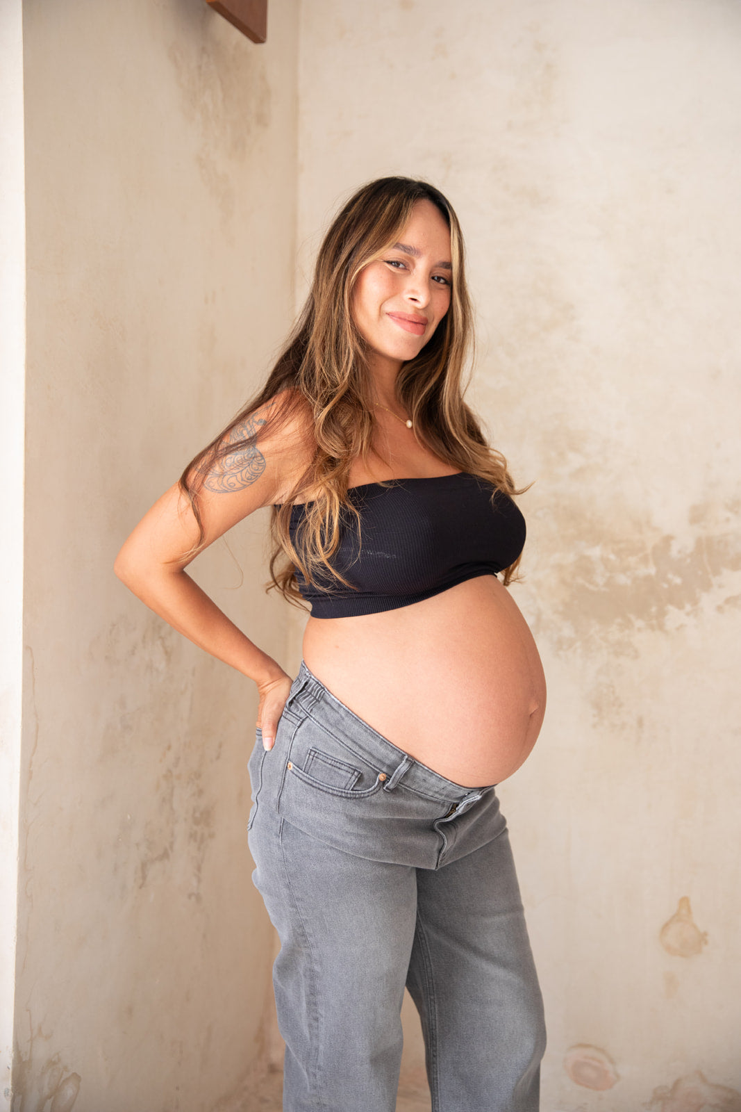 Femme enceinte qui porte un jean de grossesse gris
