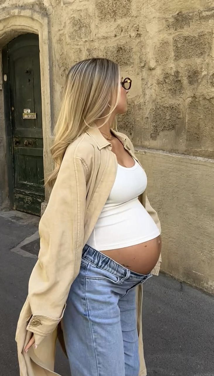 Schwangere Frau in Umstandsjeans und weißem Oberteil 
