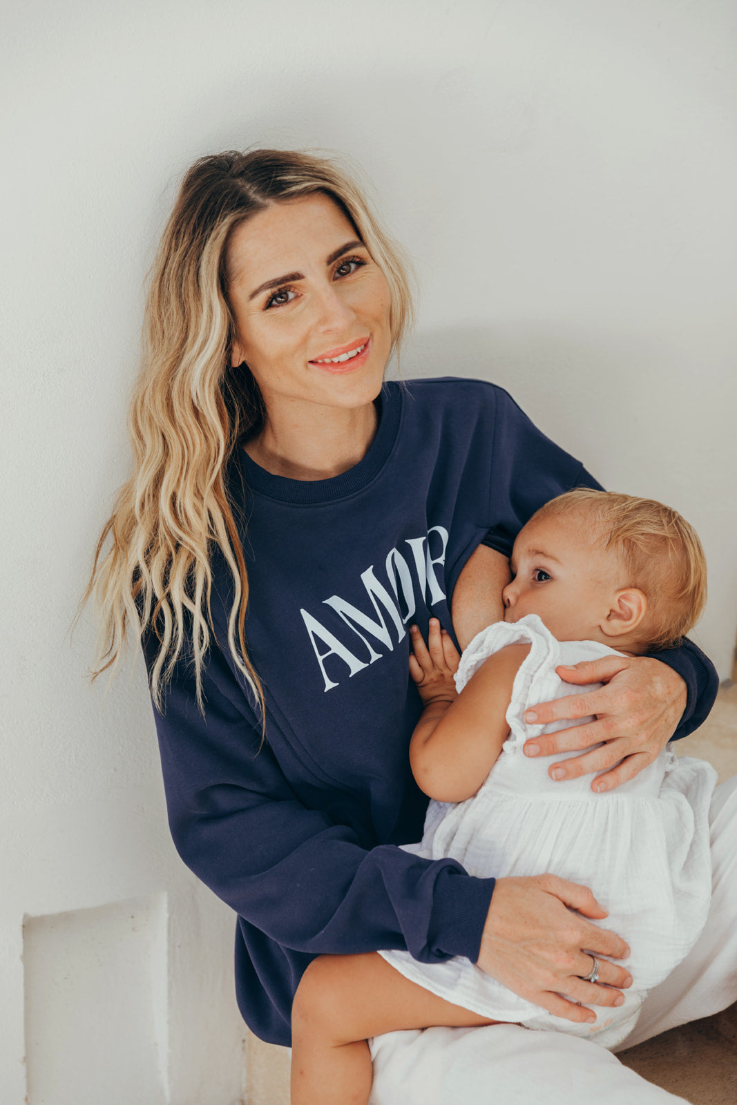 Navy blue "AMOUR" nursing sweatshirt worn by a mom holding her baby